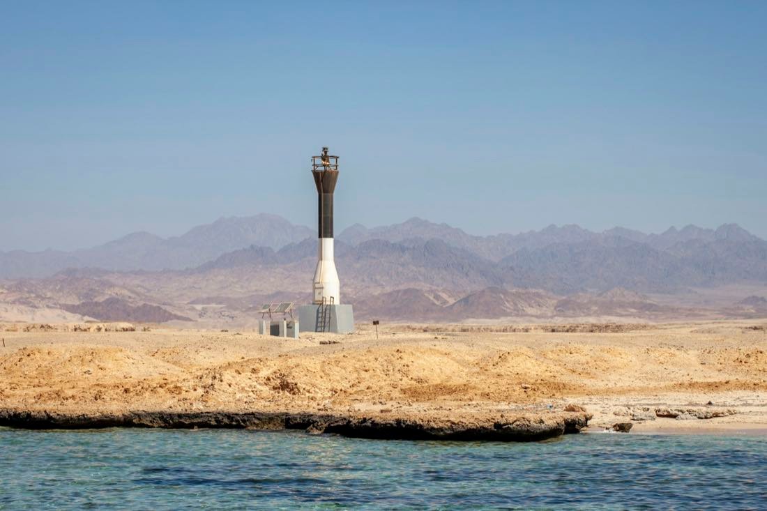 Leuchtturm an sandiger Küste, Berge dahinter — Hurghada · Ägypten